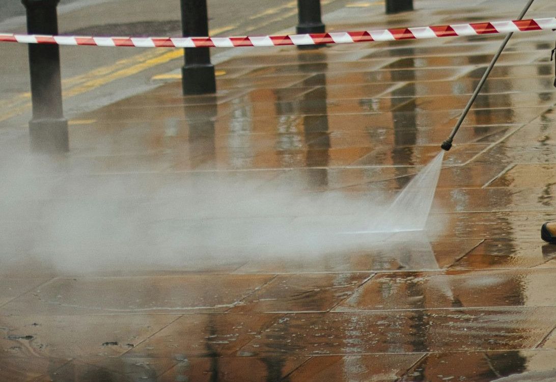 a man in a yellow jacket is using a pressure washer