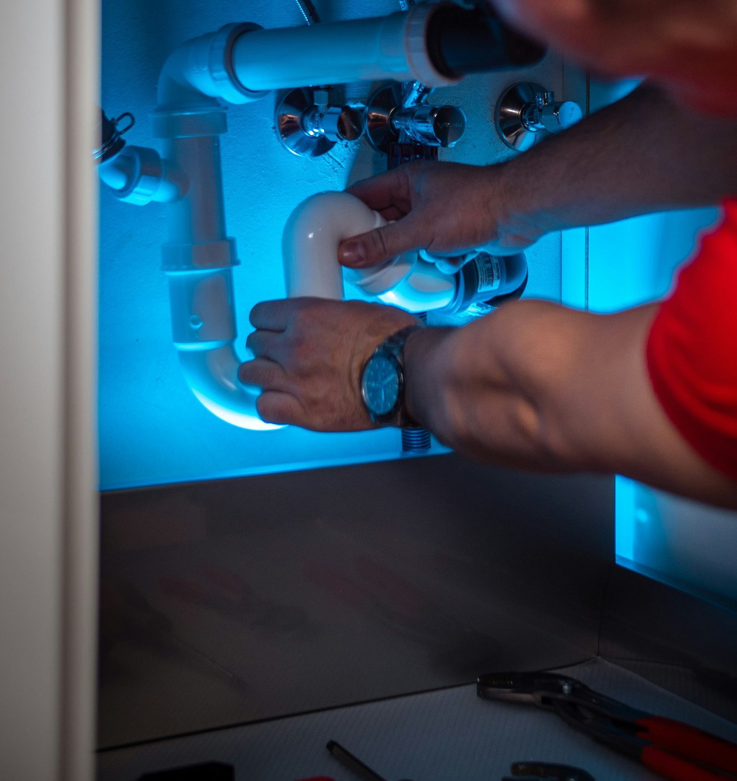 a man working on a pipe in a cabinet