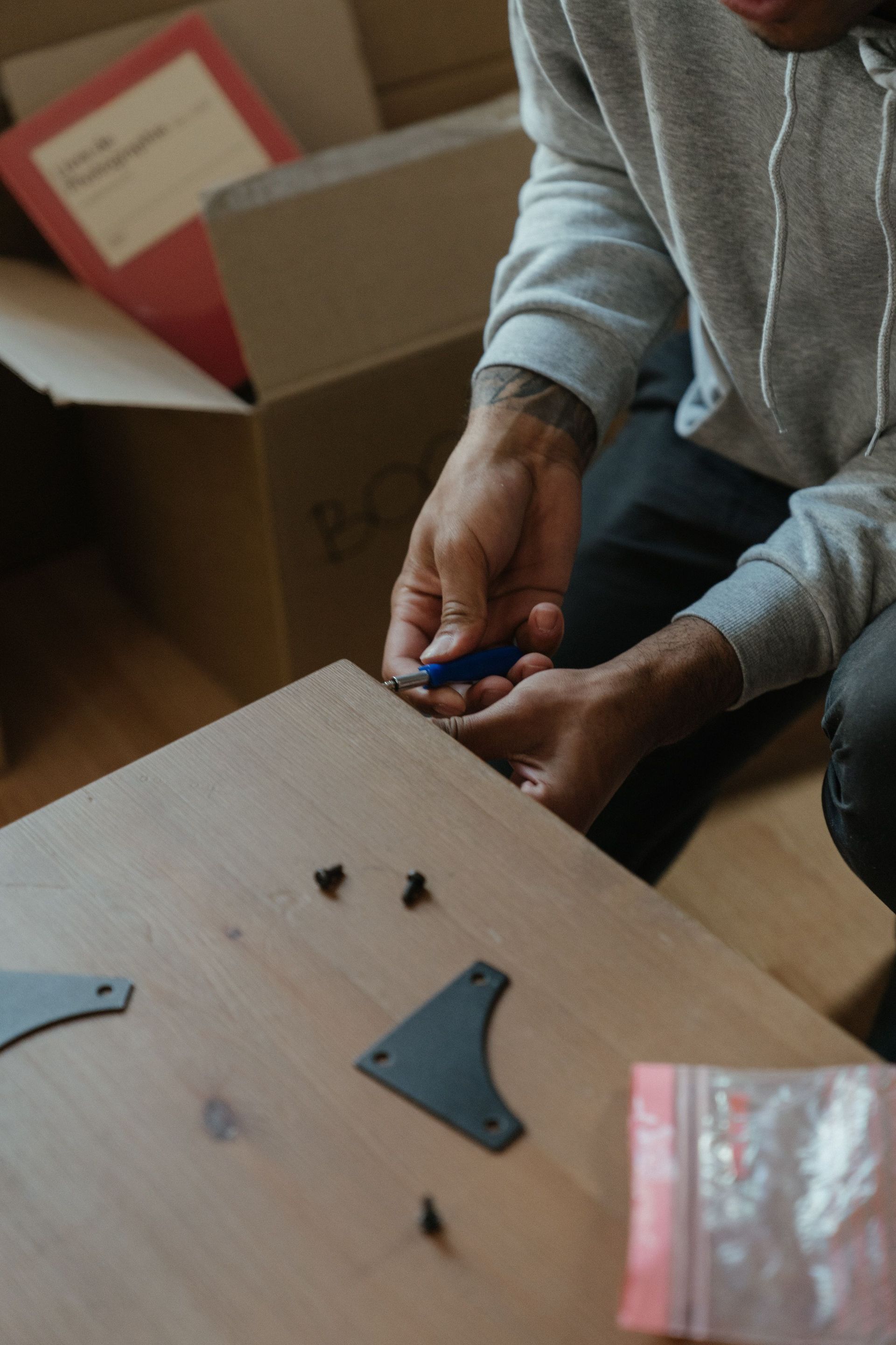 A man assembling a piece of furniture in a newly moved-in apartment setting.